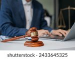 Justice and law concept.Male judge in a courtroom the gavel, working with digital tablet computer on wood table.