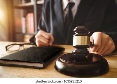 justice and law concept.Male judge in a courtroom with the gavel,working with,digital tablet computer docking keyboard,eyeglasses,on wood table in morning light
