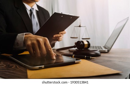 Justice and law concept.Male judge in a courtroom with the gavel, working with, computer and docking keyboard, eyeglasses, on table in morning light - Shutterstock ID 1930513841