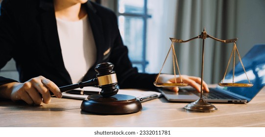 Justice and law concept.Male judge in a courtroom with the gavel, working with, computer and docking keyboard, eyeglasses, on table in morning light - Shutterstock ID 2332011781