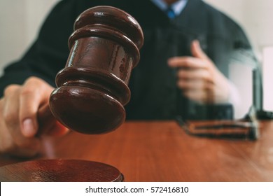 justice and law concept.Male judge in a courtroom with the gavel,working with smart phone,digital tablet computer docking keyboard,eyeglasses,on wood table