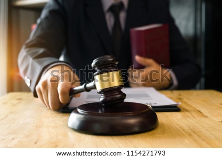 justice and law concept.Male judge in a courtroom  the gavel, working with digital tablet computer on wood table in morning light 
