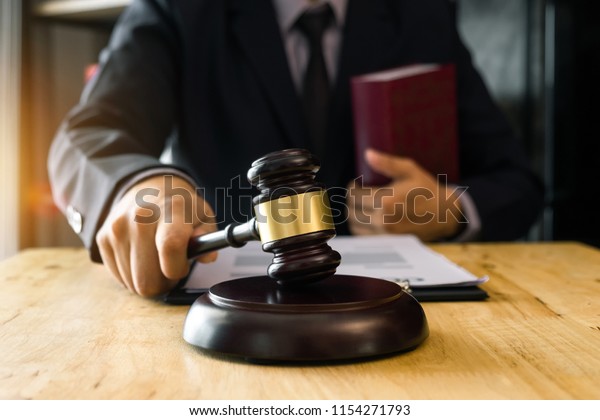 justice and law concept.Male judge in a courtroom  the\
gavel, working with digital tablet computer on wood table in\
morning light \
