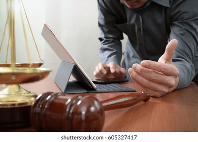 Justice And Law Concept.Male Lawyer In Office With The Gavel,working With Smart Phone And Digital Tablet Computer And Brass Scale On Wood Table