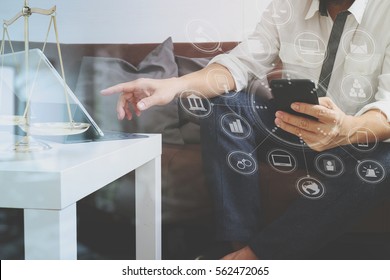 Justice and Law context.Male lawyer hand sitting on sofa and working with smart phone,digital tablet computer docking keyboard on living table at home,virtual interface graphic icons diagram