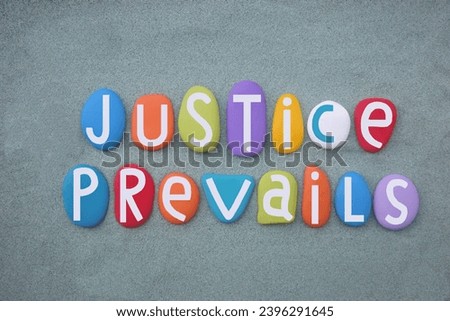 Justice Prevails, creative slogan composed with multi colored stone letters over green sand