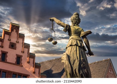 Justitia Monument view from back during dawn with sunset and clouds in background, frankfurt germany