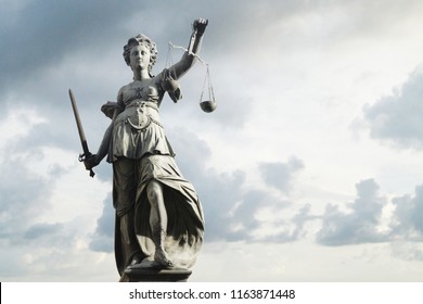 Justitia symbol of justice in front of background with sky and clouds. Concept of justice and law.