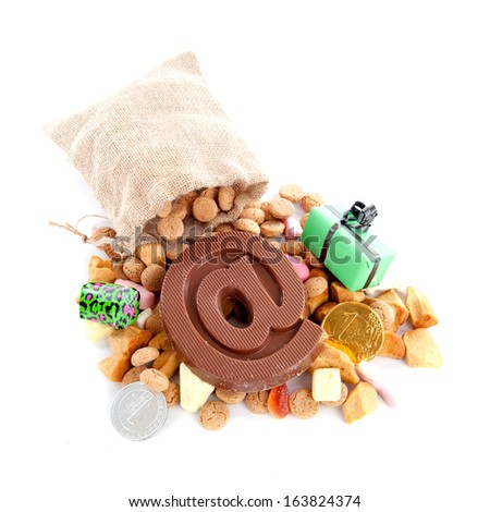 a jute bag with pepernoten, candies and a atpersand, made of chocolate on a white background