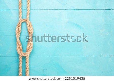 Jute rope with a knot on blue painted boards, marine backdrop, soft focus close up