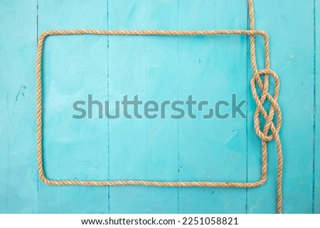 Jute rope rectangular frame, with a knot on blue painted boards, navy backdrop 