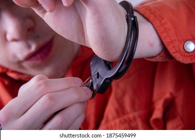 A Juvenile Delinquent Tries To Open The Handcuffs With A Paper Clip.concept: Attempt To Escape From Custody, Opening Locks, Violator Of The Law.