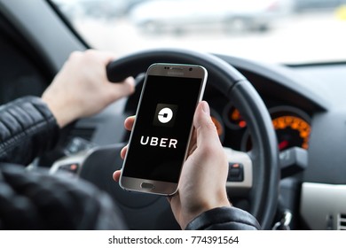 JYVASKYLA, FINLAND - DECEMBER 7, 2017: Uber driver holding smartphone in car. Uber is an American company offering transportation services online. Illustrative editorial.