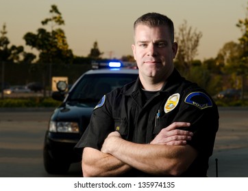 Офицер полиции К9, стоявший перед своей патрульной машиной, со скрещенными руками.