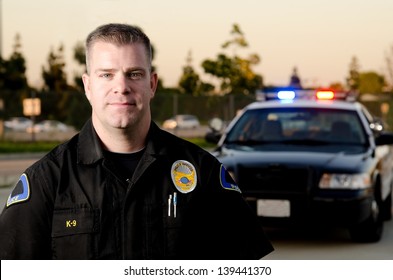 Офицер полиции К9 стоял перед своей патрульной машиной в сумерках.