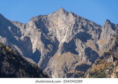 Kabardino-Balkaria. El-Tyubu. Rocky mountains with trees growing on their slopes glow in morning sun. Close-up. Chegem Gorge. Unique rocky ridge with steep cliffs against blue autumn sky. - Powered by Shutterstock