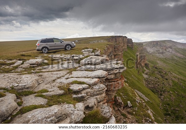 Kabardino-Balkaria region,\
Russia - August 2018:  Subaru Forester on the edge of a cliff,\
against the backdrop of a landscape in the mountains and clouds.\
Extreme car\
trips