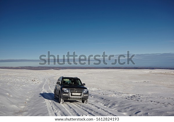 Kabardino-Balkaria, Russia - Oktober 2017:  Gray
SUV Mitsubishi Pajero on the background of pure white snow, winter
mountains and blue sky, on a bright sunny day. Travel by car on the
road.