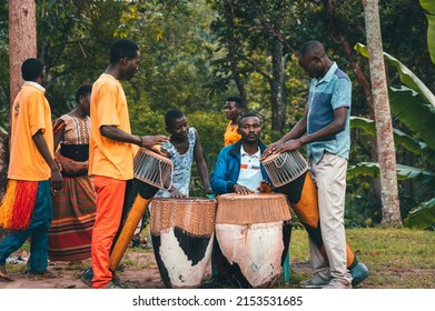 Kabarole, Uganda - January 2, 2022: Young African people of Batwa tribe, playing on the drums outdoors in the forest