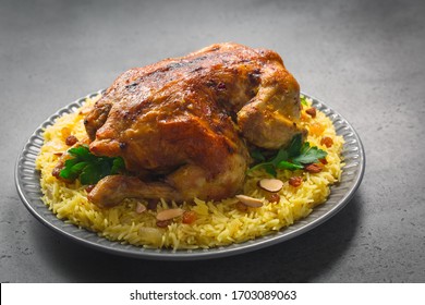 Kabsa - Arabian Dish Made Of Long Grain Basmati Rice, Whole Chicken, Onion, Spices: Cardamom, Saffron, Cinnamon, Bay Leaves.  Decorated With Almonds And Raisins. Saudi Arabia Food. Grey Background