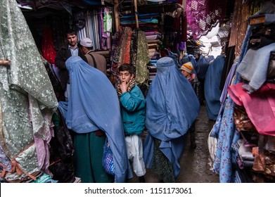 Kabul, Afghanistan, March 2005: Woman Looking At Cloth In Kabul Market Stall