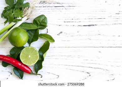 Kaffir Lime Leaves, Fruit, Coriander Or Cilantro, Red Chilli And Green Onions Over White Distressed Wooden Background. Overhead View.