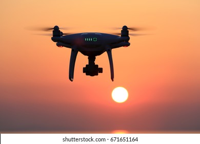 KAGAWA, JAPAN - JUNE 15, 2017: Remote controlled drone Dji Phantom 4 Pro equipped with high resolution video camera flying in air and sunset orange sky.