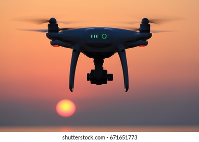 KAGAWA, JAPAN - JUNE 15, 2017: Remote controlled drone Dji Phantom 4 Pro equipped with high resolution video camera flying in air and sunset orange sky. 