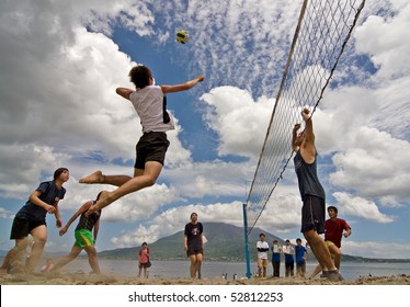 KAGOSHIMA CITY, JAPAN - JULY 6: A male volleyball player jumps to spike  at the  Iso Beach beach volleyball competition July 6, 2007 in Kagoshima City. Active volcano Sakurajima is in the background.