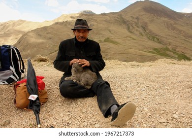 Kailash Area Tibet China - 06 18 2008: Tibetans Pilgrim. A Man In Black Clothes And Wearing A Hat With A Cat Rests On A Mountain Top In Tibet