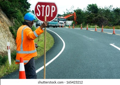 KAITAIA, NZ - NOV 05 2013:Road Worker Slows Traffic With Stop Sign.The Road Maintenance Crew Has The Responsibility For The Day-to-day Maintenance Needs Of The Road System.