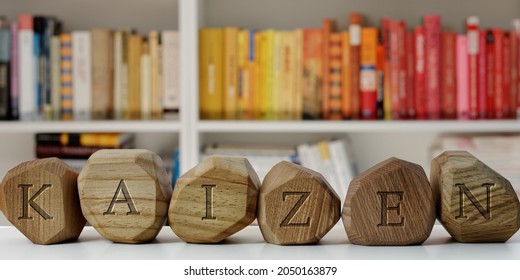 Kaizen word  (Japanese meaning: change for better) on blocks in home library, blurred books background. Kaizen concept of continuous improvement strategy.