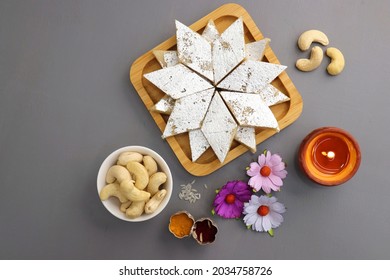Kaju Katli is a traditional Indian Diamond shaped sweet or Mithai made using cashew paste, sugar, and mava or Khoya. served in a wooden plate over dark background. cashew barfi. Copy space