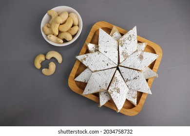 Kaju Katli is a traditional Indian Diamond shaped sweet or Mithai made using cashew paste, sugar, and mava or Khoya. served in a wooden plate over dark background. cashew barfi. Copy space
