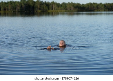 Kakerdaja / Estonia - August 01 2020: Teenager Blonde Girl Swimming In Bog Lake. Hands And Feet Spread Out. Human Body Floating In Pool. 