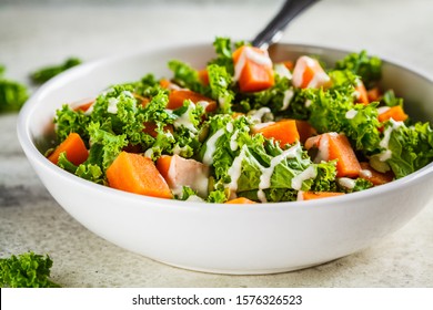 Kale And Baked Sweet Potato Salad With Tahini Dressing In White Bowl.