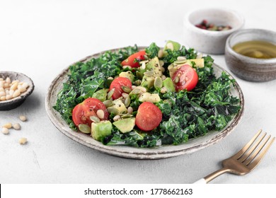 Kale Salad With Cherry Tomatoes, Avocado, Pine Nuts And Pumpkin Seeds On A White Background