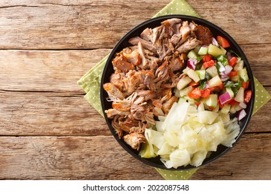 Kalua pork hawaiian food slowly cooked and served with stewed cabbage and fresh salad close-up in a plate on the table. horizontal top view from above