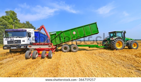 Kalush,\
Ukraine - August 12: Overloading the grain silo tractor trailer in\
the car using auger tractor-drawn auger loader in the field near\
the town Kalush, Western Ukraine August 12,\
2015