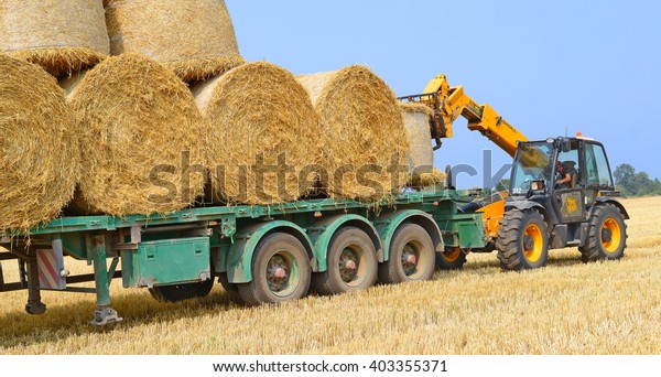 Kalush, Ukraine - August 14: Loading bales of straw\
on the car in the field near the town Kalush, Western Ukraine\
August 14, 2015