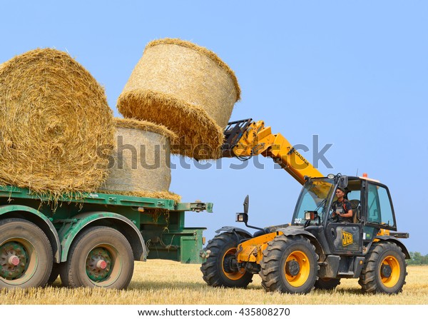 Kalush, Ukraine - August 14: Loading bales of straw\
on the car in the field near the town Kalush, Western Ukraine\
August 14, 2015