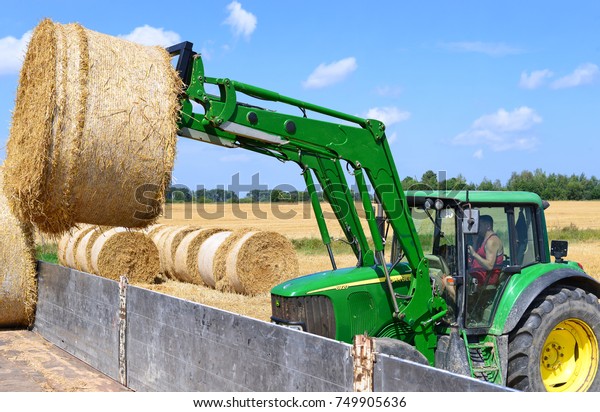 Kalush, Ukraine - July 30: Loading bales of\
straw in the car tractor with attachments in the field near the\
town Kalush, Western Ukraine July 30,\
2016