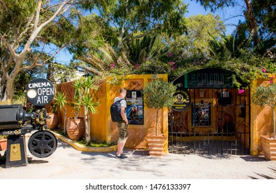 Kamari, Santorini / Greece: 18JUL2019:Santorini, Kamari Town Open Air Cinema. Main Entrance Of The Cinema Exterior And Man Tourist Looking At Cinema Program.