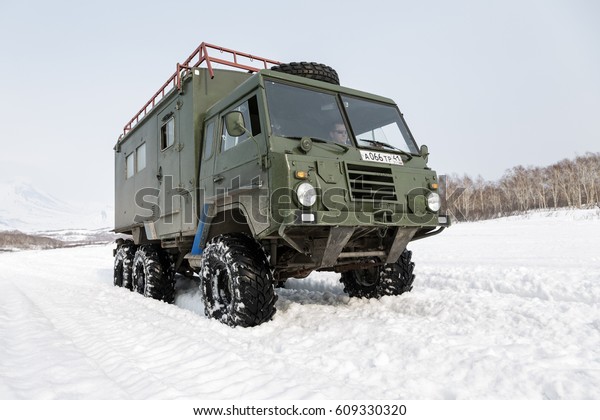KAMCHATKA PENINSULA, RUSSIAN FEDERATION - APR 04,\
2014: Old Swedish military car Volvo Laplander C304 (6WD) khaki\
color, used in Kamchatka Peninsula as a touristic, rides in snow\
along a country road.