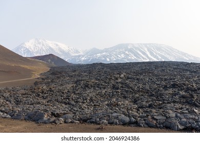 Kamchatka rocks from volcanic rocks multi-colored volcanic rocks. Crumbling volcano craters. against the backdrop of volcanoes with peaks in the snow and clouds. Ostry Tolbachik and Plosky Tolbachik. - Shutterstock ID 2046924386
