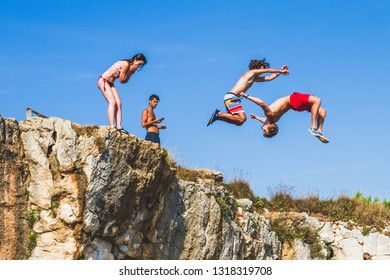 KAMENJAK PARK, CROATIA - AUGUST 2017 - Two Boys Jump From A Cliff While A Girl Watch Them Very Scared