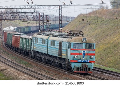 Kamianske, Ukraine - Autumn 2021: An Old VL8 Electric Locomotive Pulls A Long Freight Train To The Railway Station Along A Winding Road. Cloudy Autumn Weather. Ukrainian Railway