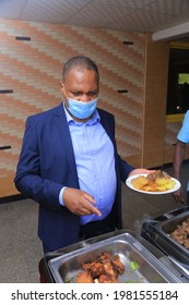 Kampala, Central, Uganda 26-05-2021
 African American Man  Dressed In A Suite With No Tie On The Line Getting Food At The Wedding Ceremony With His Face Mask On His Face