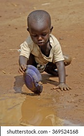 Kampala, Uganda-10 April 2007: Thirsty and hungry child is trying to get some water in a dirty pool.