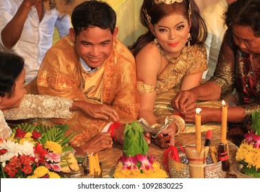 Kampong Tom, Cambodia, 04-10-2014, The Wedding Guests Tie Red Cotton On The Wrists Of The Bride And Groom And Place Good Luck Money In The Joined Hands.